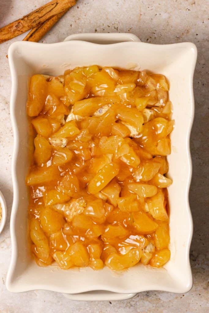 place apple pie filling onto cut cinnamon rolls in casserole dish 