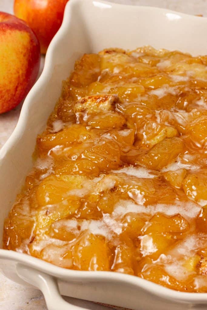 drizzling cream cheese icing onto baked cinnamon roll apple cobbler
