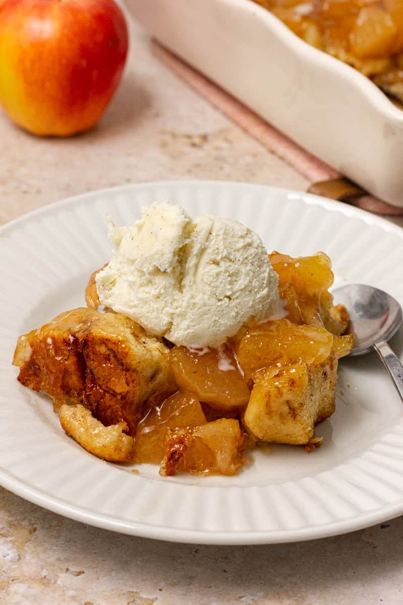 cinnamon roll apple cobbler on white place with scoop of ice cream