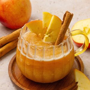 apple cider slushie in a glass mug garnished with apples and cinnamon stick