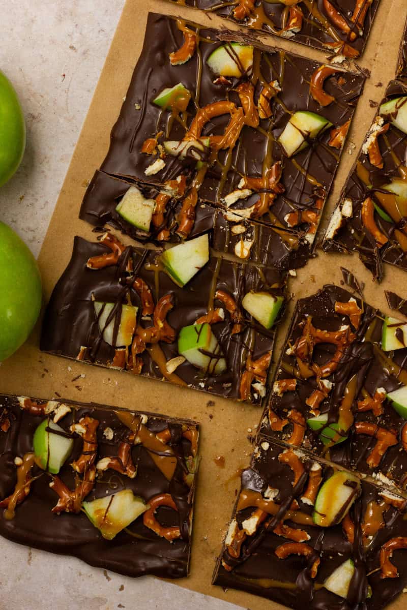 Chocolate apple bark broken into pieces on parchment paper.