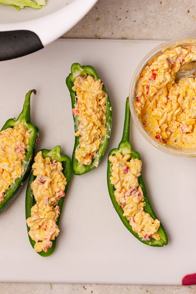 stuffing jalapeno peppers with pimento cheese on a cutting board