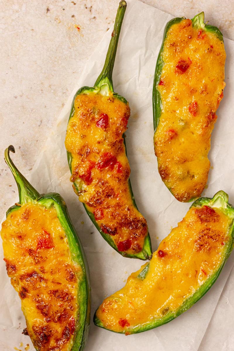 pimento cheese jalapeno poppers on a table with parchment paper