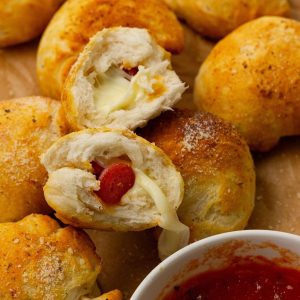 Cheese and pepperoni-filled dough balls with a small bowl of marinara sauce on the side.