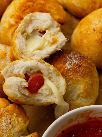 Cheese and pepperoni-filled dough balls with a small bowl of marinara sauce on the side.