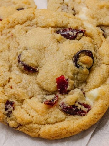 Close-up of Cranberry Orange White Chocolate Cookies with golden edges, dried cranberries, and white chocolate chunks.