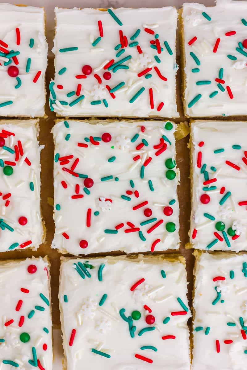 Frosted Christmas sugar cookie bars are sliced into squares and topped with red, green, and white sprinkles.