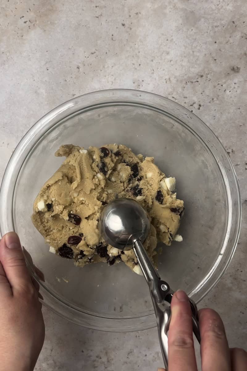 Cookie dough being portioned with a scoop for even baking.