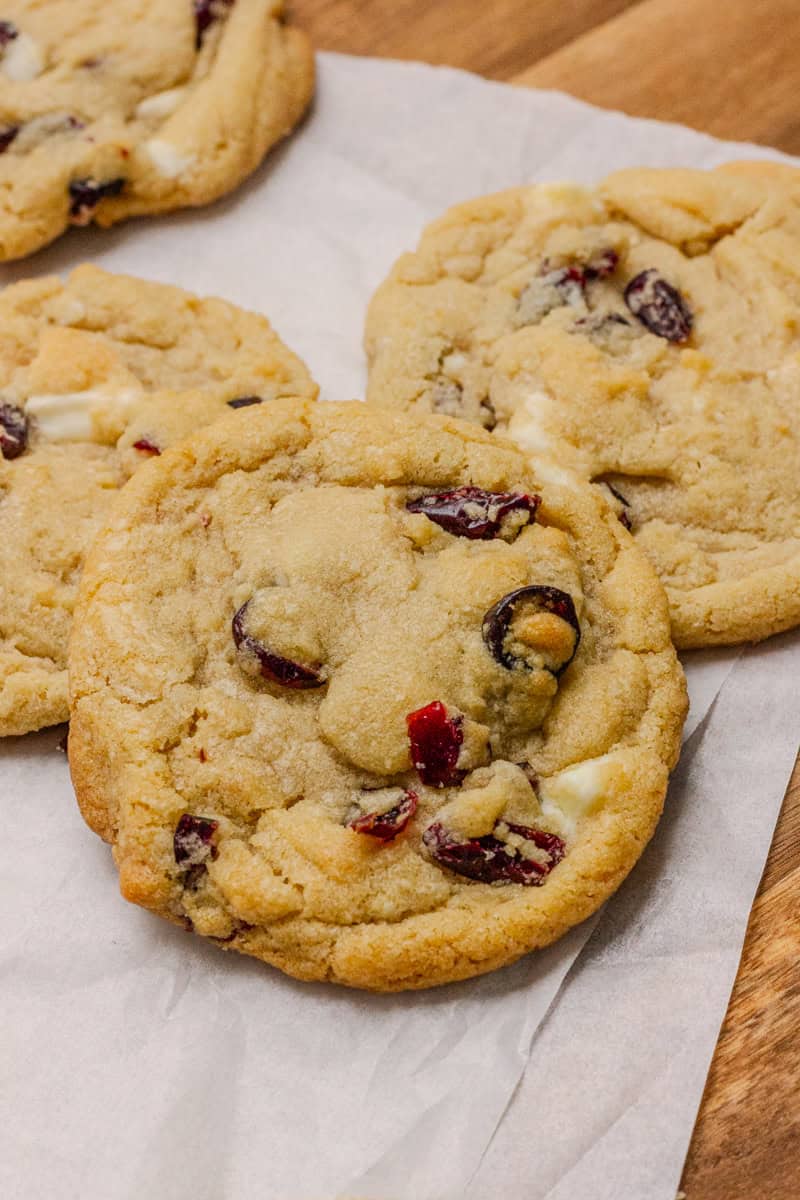 Freshly baked Cranberry Orange White Chocolate Cookies on parchment paper.