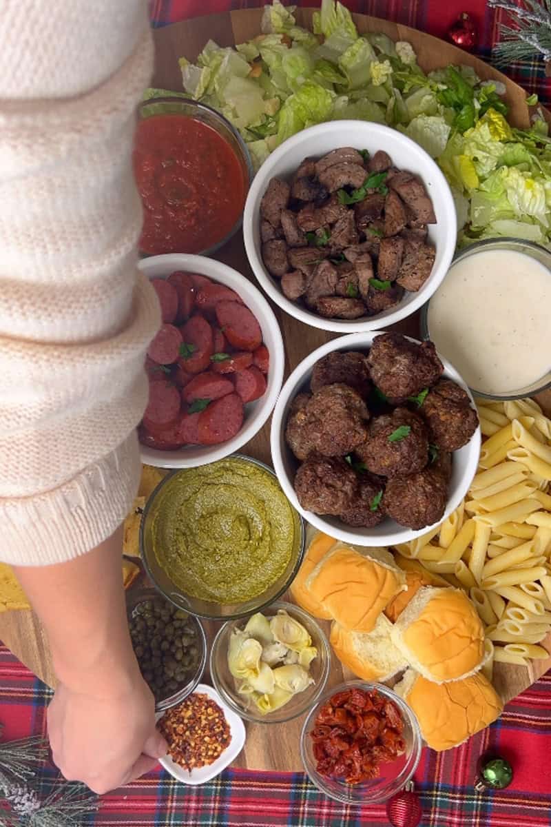 Filling out the board with bread, Caesar salad, and various toppings to complete the spread.