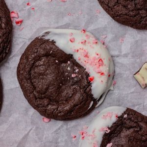 Close-up of a fudgy peppermint bark brownie cookie surround by cookies and bark pieces.