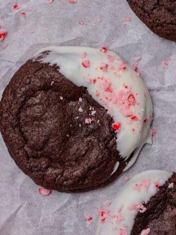 Close-up of a fudgy peppermint bark brownie cookie surround by cookies and bark pieces.