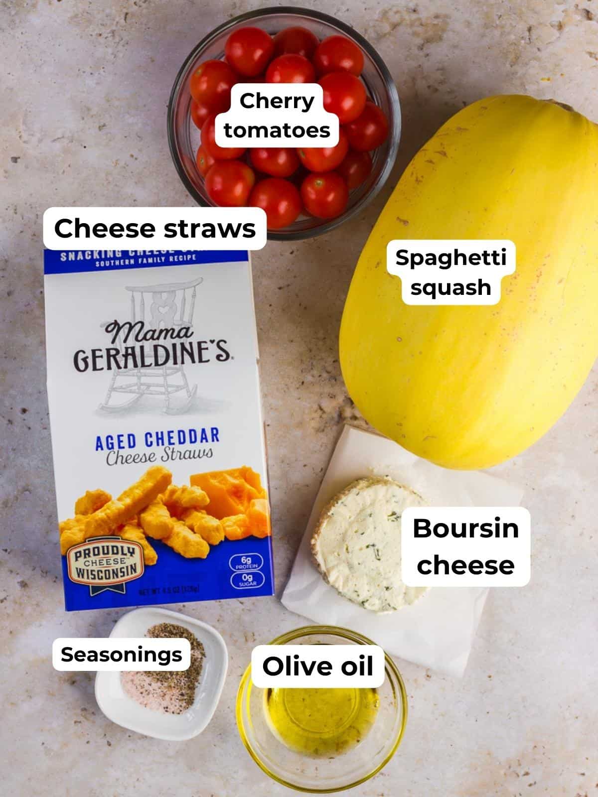 Ingredients on a table: cherry tomatoes in a bowl, spaghetti squash, cheese straws box, Boursin cheese, seasonings, and olive oil in a small bowl.