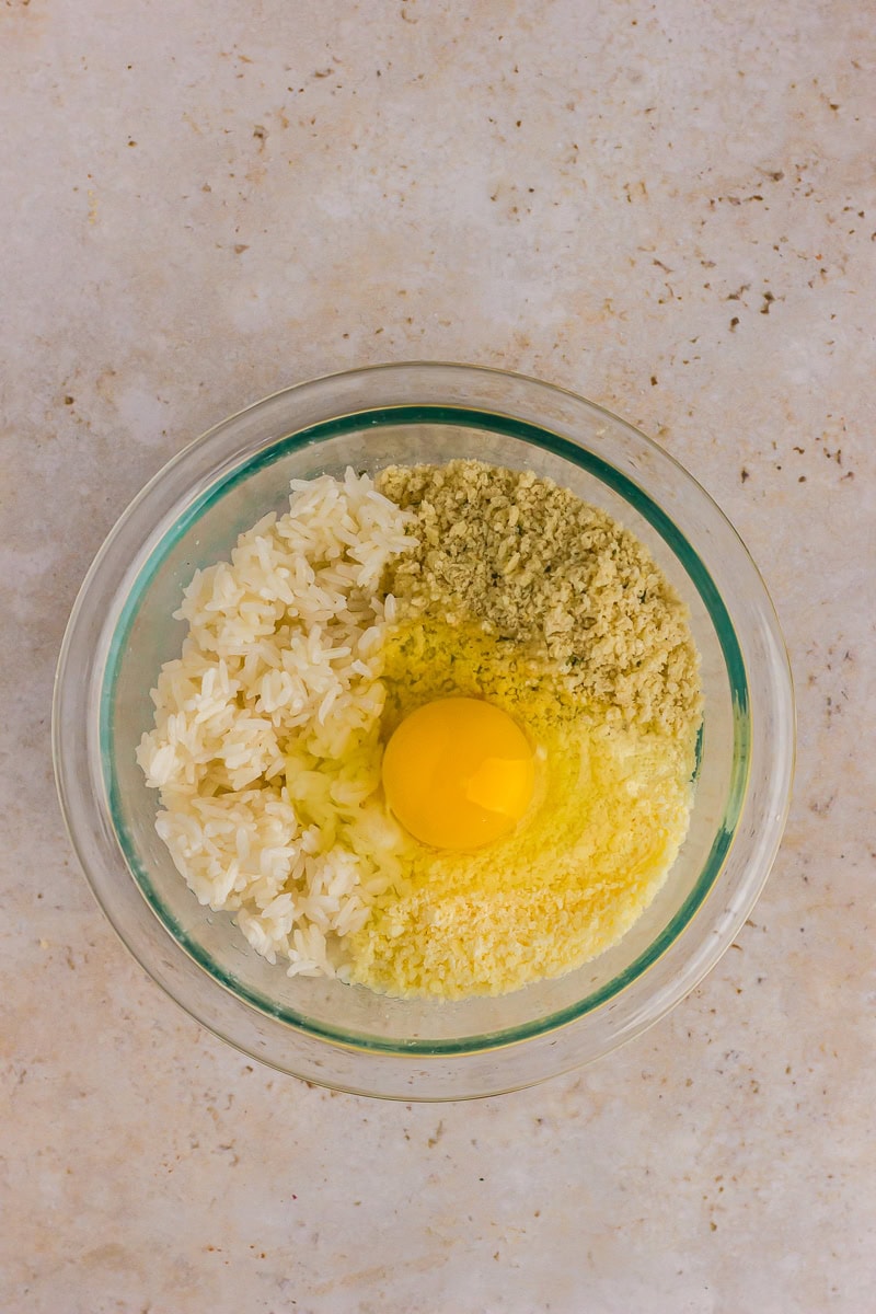 Rice, breadcrumbs, Parmesan, and egg combined in a mixing bowl.