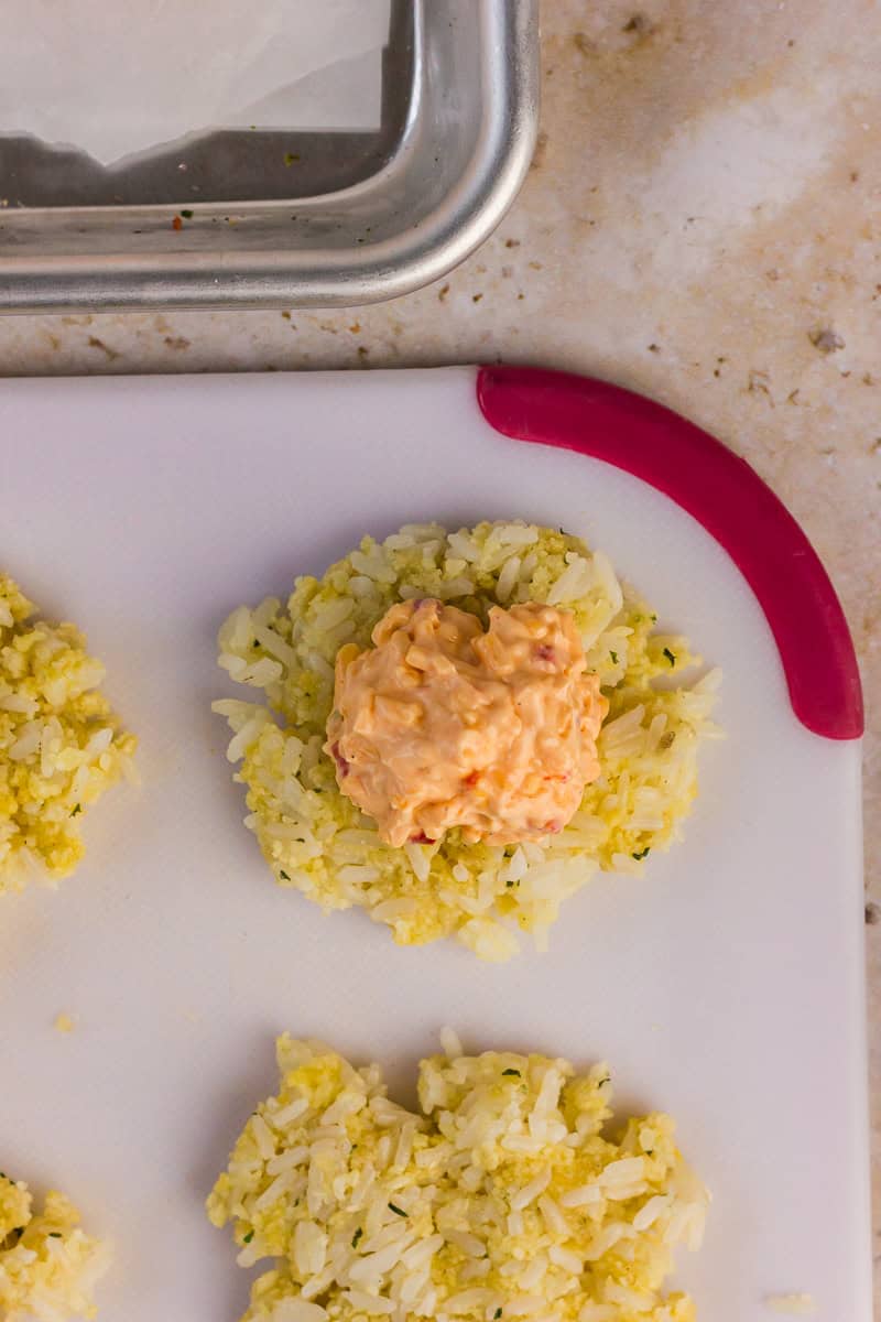 Flattened rice patty with a pimento cheese scoop in the center.