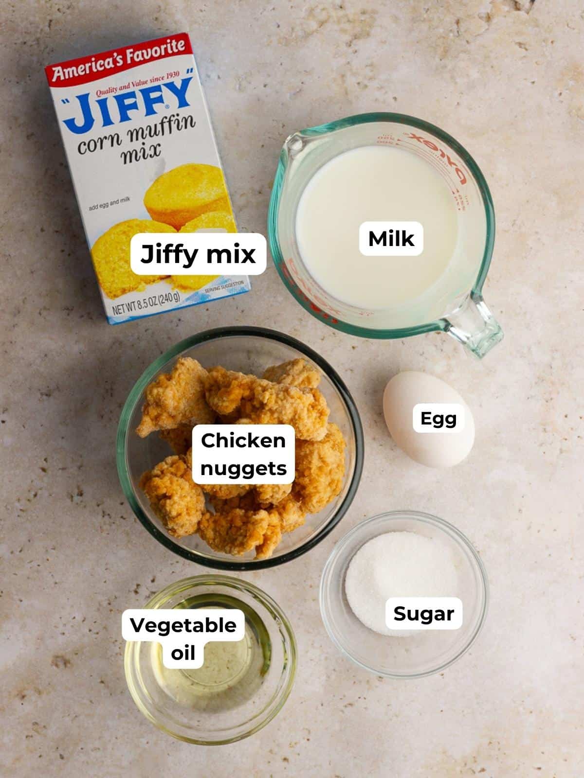 Ingredients for cornbread waffles and chicken, including Jiffy mix, milk, egg, sugar, vegetable oil, and frozen chicken nuggets, labeled in bowls.