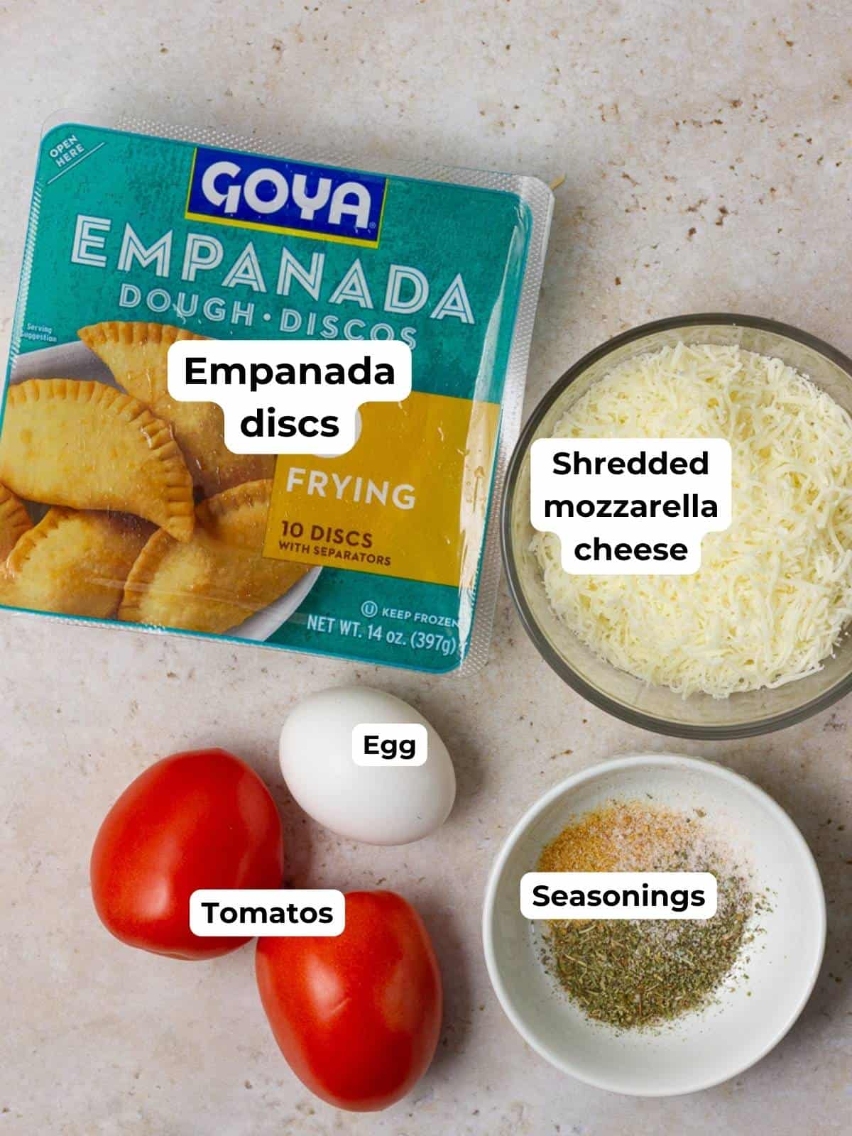 Ingredients for empanadas caprese, including empanada discs, shredded mozzarella, eggs, Roma tomatoes, and seasonings.