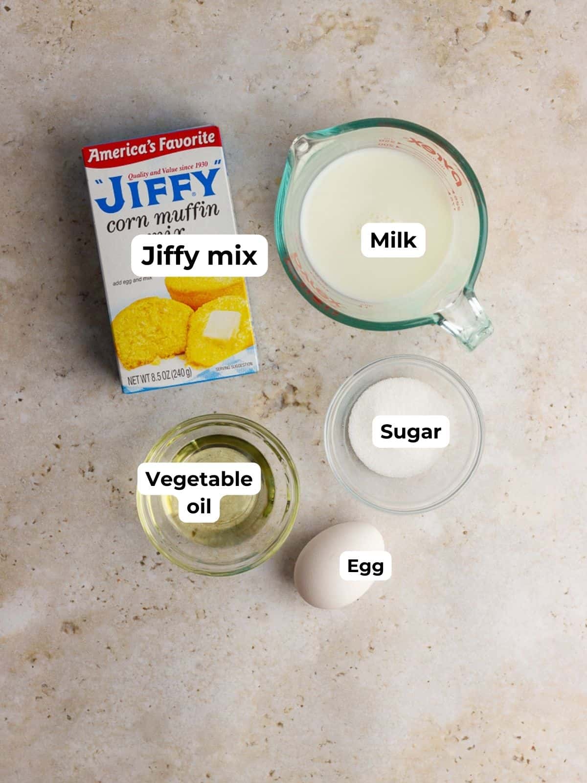 Ingredients for Jiffy cornbread waffles, including Jiffy mix, milk, egg, sugar, and vegetable oil, labeled in small bowls.