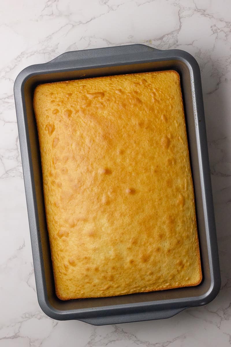 A freshly baked vanilla cake in a rectangular baking pan, ready to be crumbled for cake pops.