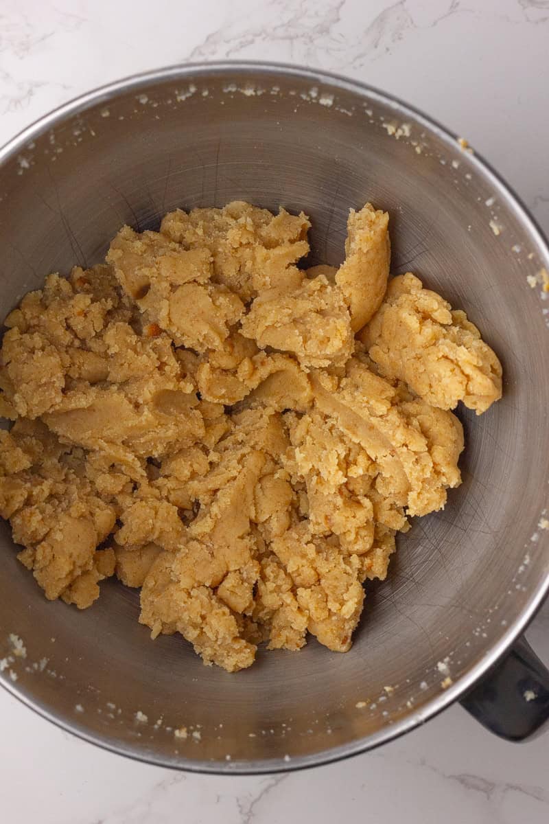 A mixing bowl filled with crumbled vanilla cake and powdered sugar, forming the cake pop mixture.