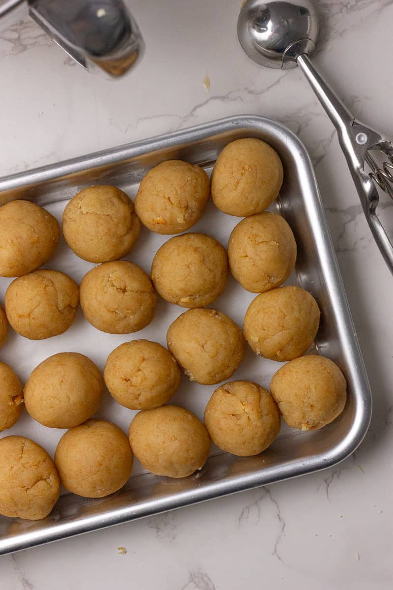 A tray lined with parchment paper holding evenly rolled cake balls, prepped for dipping.