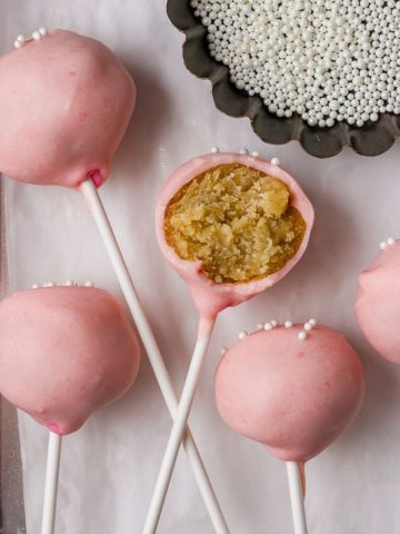 A close-up of pink cake pops with a smooth chocolate coating and white sprinkles, showcasing the final product.