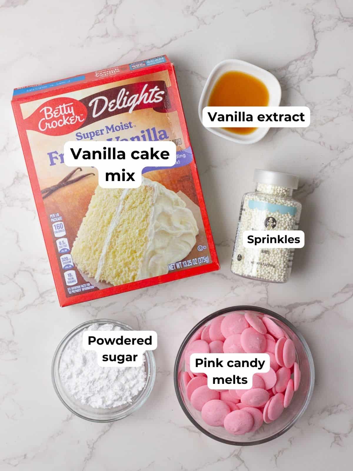 Labeled ingredients for pink cake pops, including vanilla cake mix, powdered sugar, pink candy melts, vanilla extract, and sprinkles.