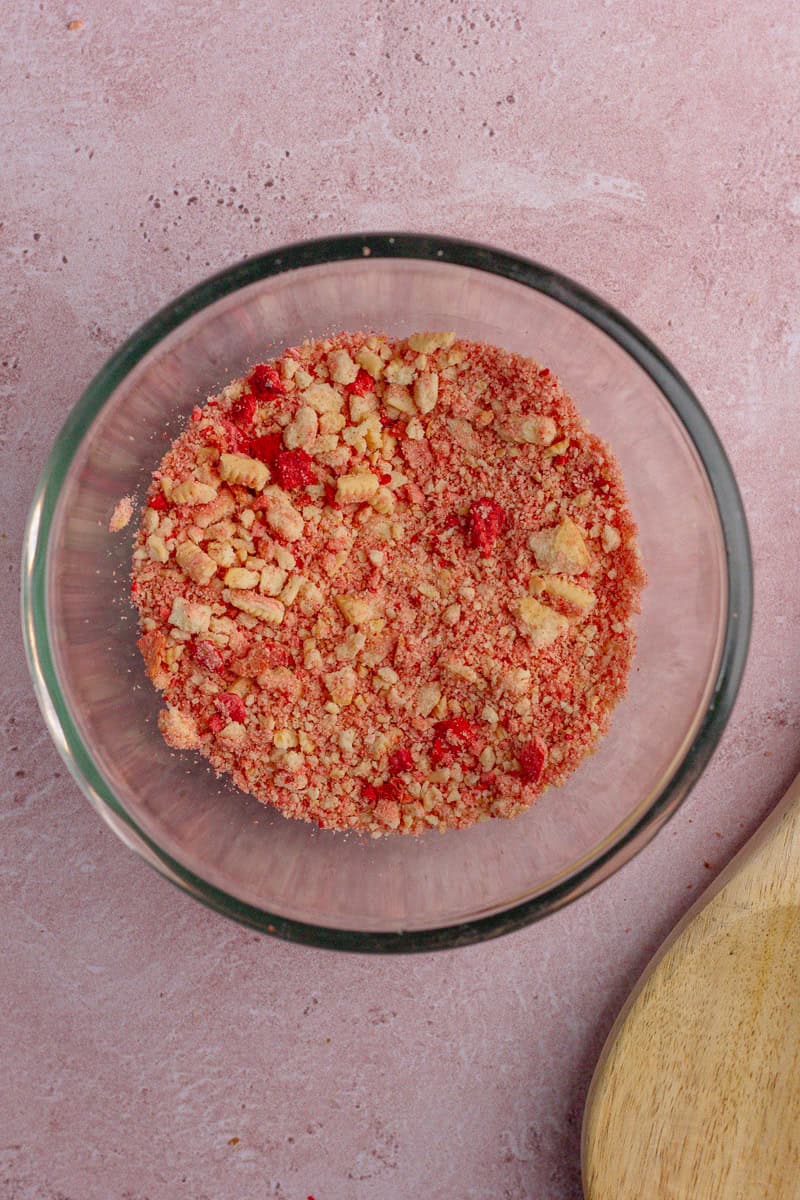 A bowl of crushed freeze-dried strawberries and golden sandwich cookies.