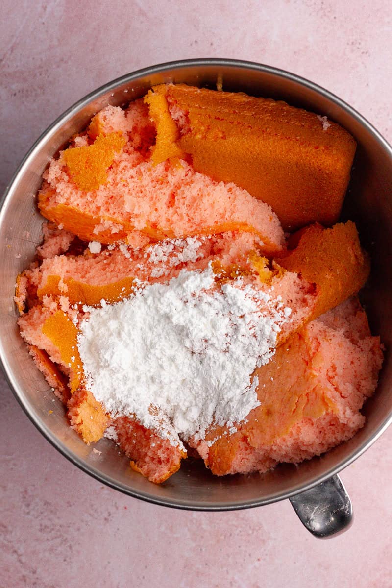A mixing bowl filled with crumbled baked strawberry cake and powdered sugar.