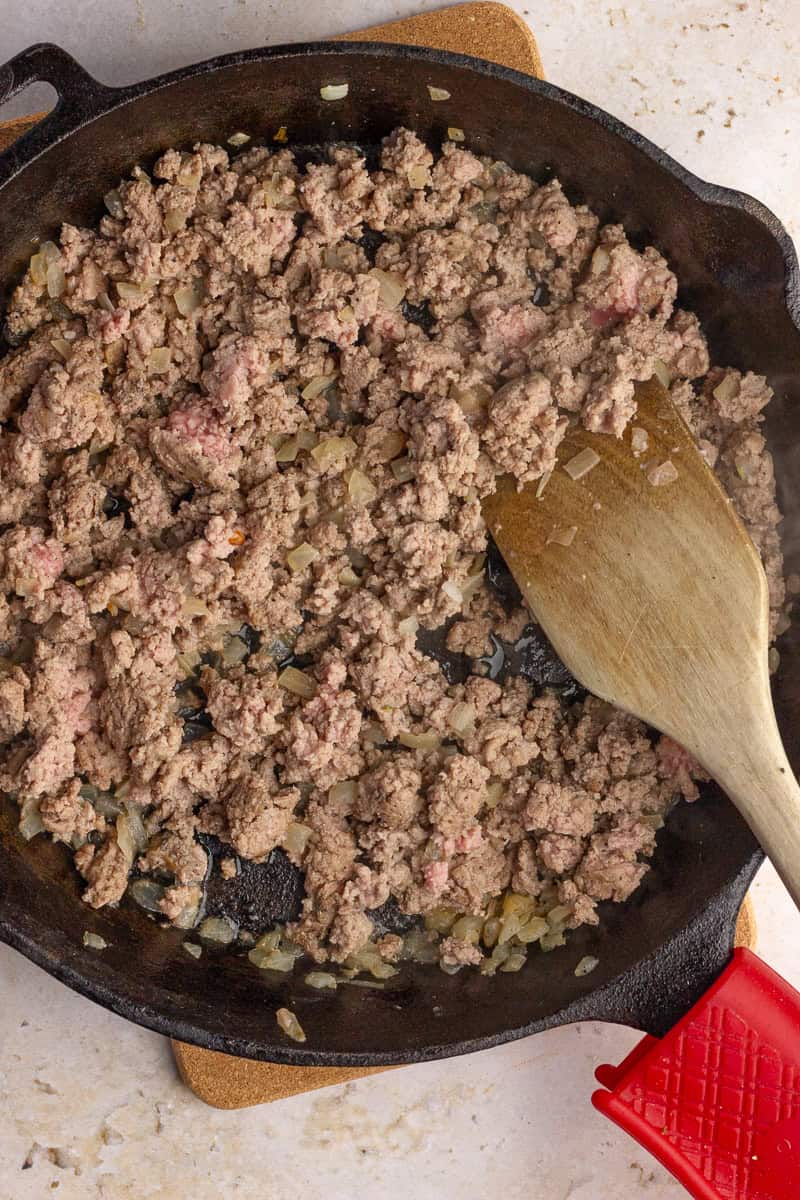 Ground turkey and onions cooking in a cast iron skillet.