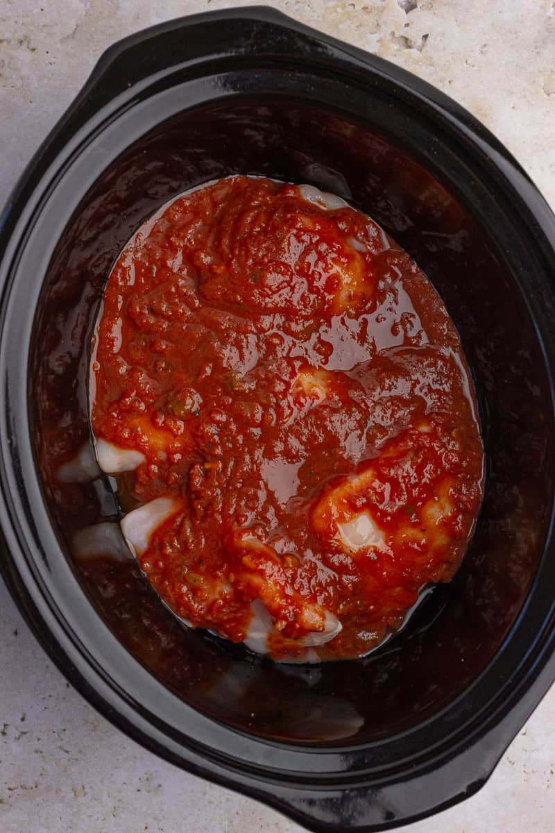 Chicken breasts covered in salsa inside a crock pot, ready to cook.