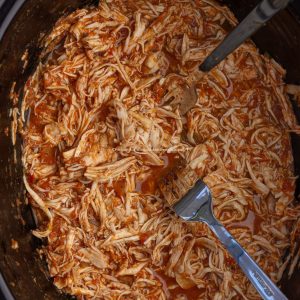 Shredded crock pot chicken for enchiladas in a slow cooker, ready to serve.