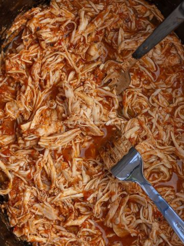 Shredded crock pot chicken for enchiladas in a slow cooker, ready to serve.