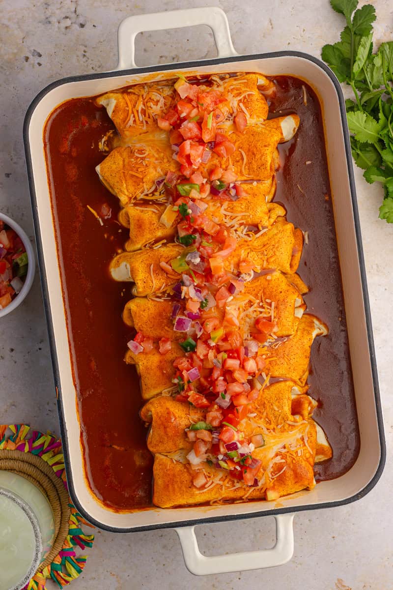 Overhead of cheesy enchiladas topped with fresh pico de gallo.