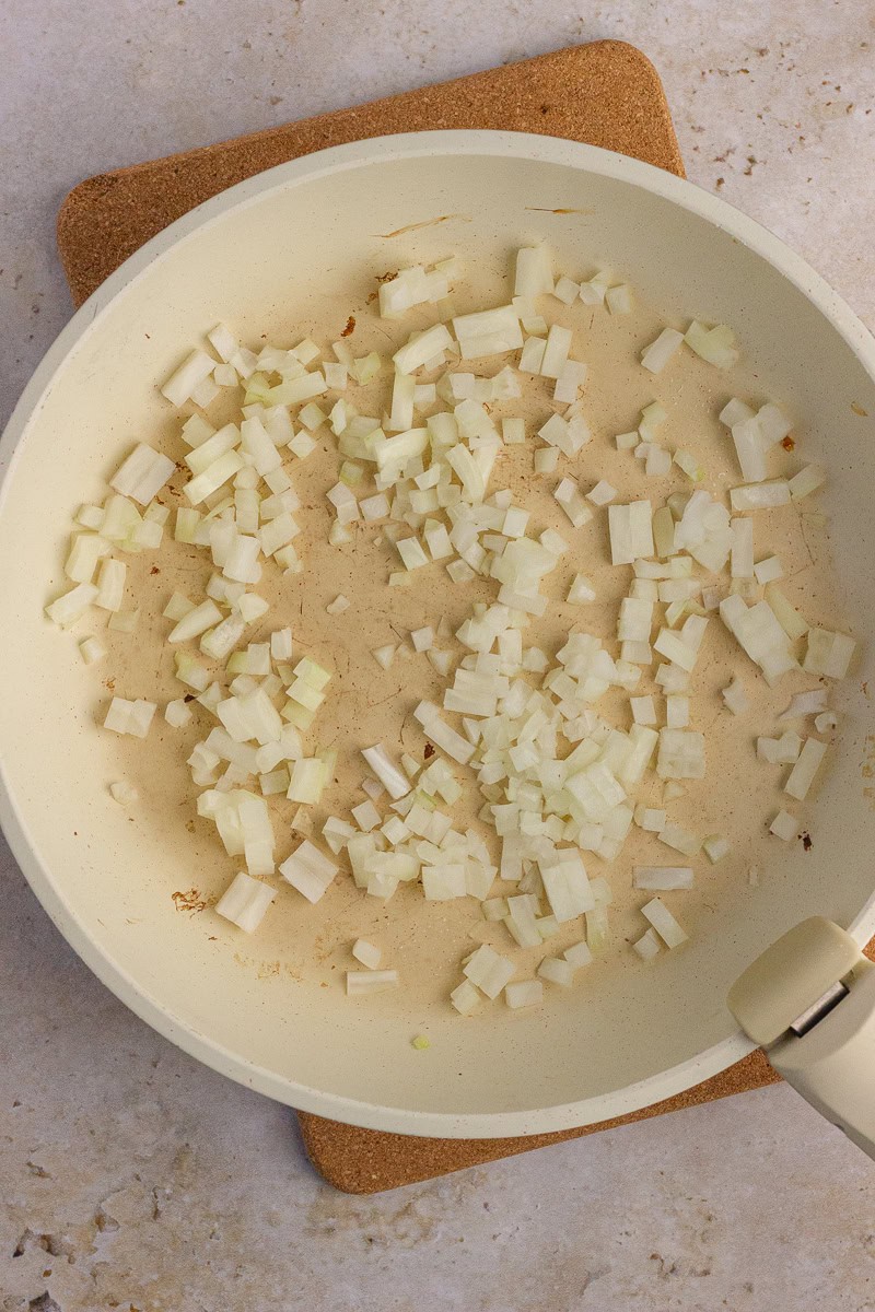 Diced onions sautéing in a pan to start the chicken pot pie filling.