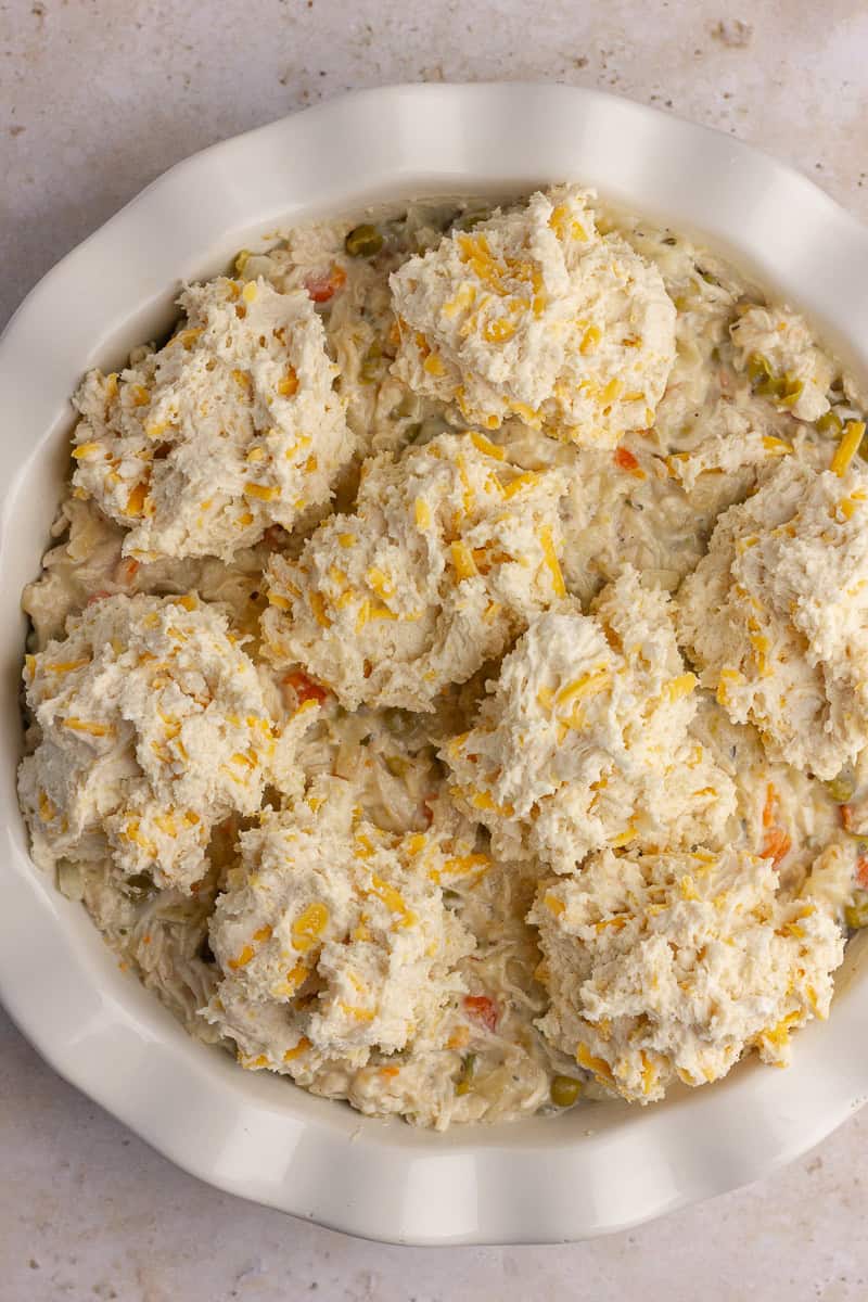 Unbaked cheddar biscuit dough scooped over the creamy chicken pot pie filling.