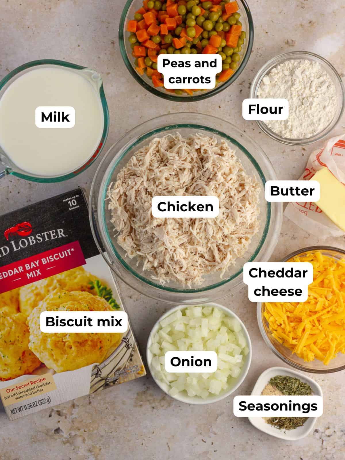 Ingredients laid out for making Cheddar Bay Biscuits Chicken Pot Pie, including biscuit mix, shredded chicken, vegetables, and seasonings.