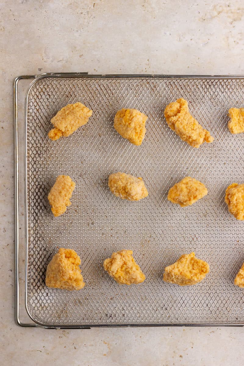 Frozen chicken nuggets arranged on an air fryer tray, ready to be cooked.