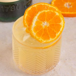 A close-up of the final cocktail with vibrant orange slices on top, with a Jameson Orange bottle in the background.
