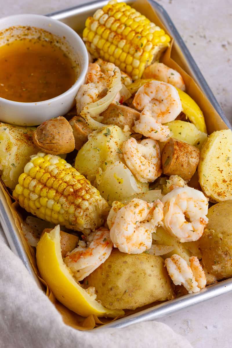 A finished shrimp boil served on a tray with a side of melted butter for dipping.