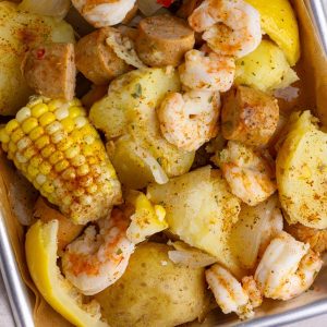 A top-down view of a shrimp boil featuring shrimp, potatoes, sausage, and corn.