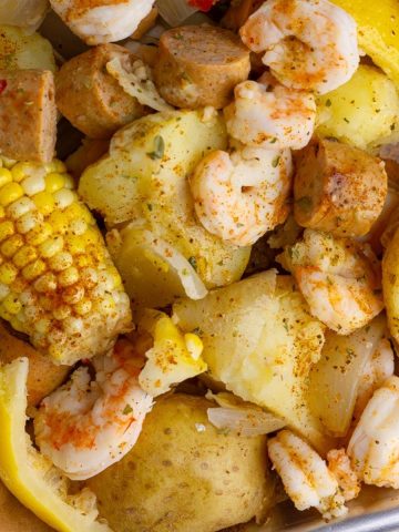 A top-down view of a shrimp boil featuring shrimp, potatoes, sausage, and corn.