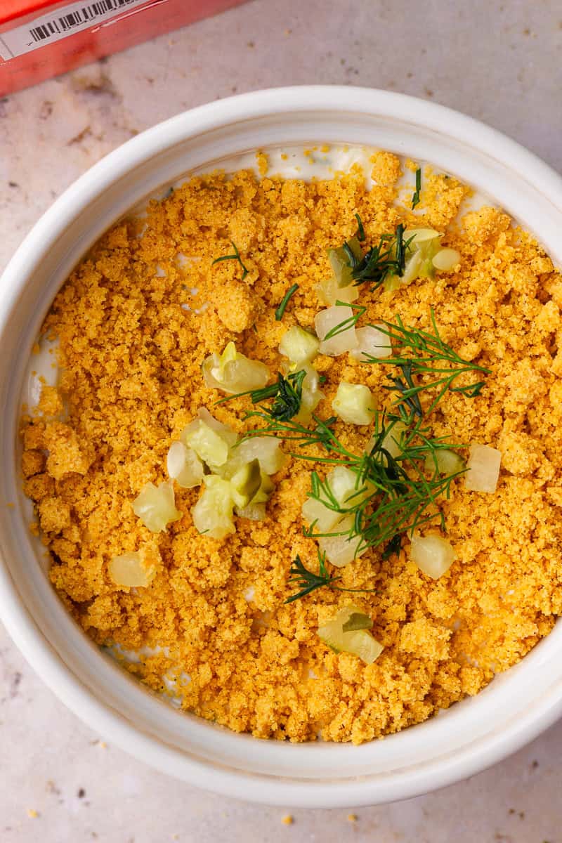 Close-up of Southern Fried Pickle Dip topped with crushed cheese straws, diced pickles, and fresh dill.