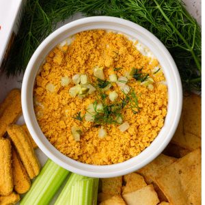 Southern Fried Pickle Dip garnished with crushed cheese straws, fresh dill, and diced pickles surrounded by dippers.