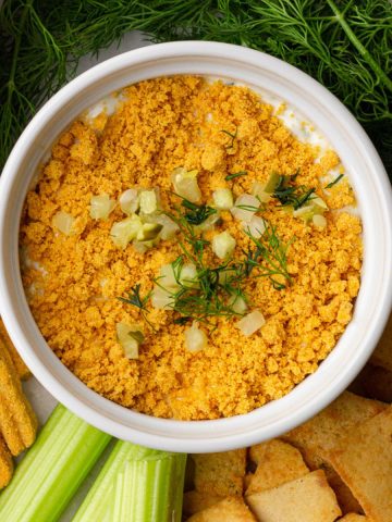 Southern Fried Pickle Dip garnished with crushed cheese straws, fresh dill, and diced pickles surrounded by dippers.