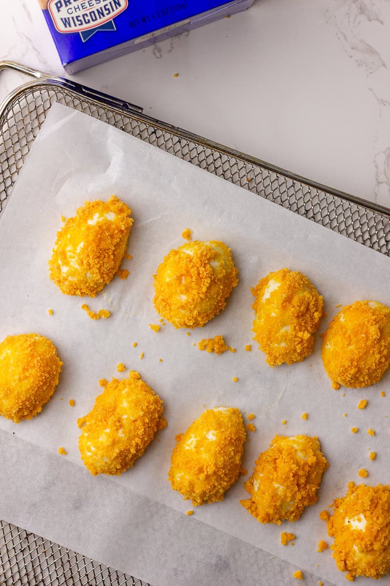Coated egg white halves arranged on parchment-lined air fryer tray before cooking.