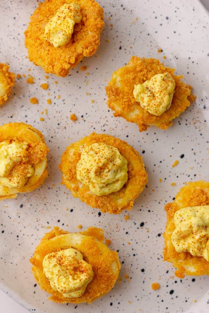 Fully assembled air fryer deviled eggs with crispy coating and creamy filling, sprinkled with paprika.