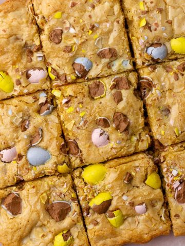 A top-down view of sliced Cadbury egg cookie bars on parchment paper.
