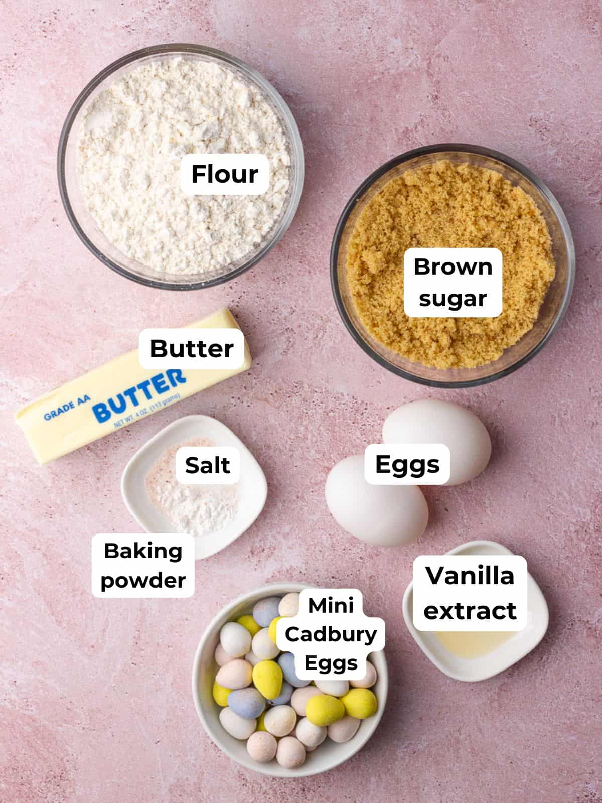 All ingredients for Cadbury Egg Cookie Bars are labeled and arranged, including flour, brown sugar, butter, eggs, vanilla, salt, baking powder, and mini Cadbury eggs.