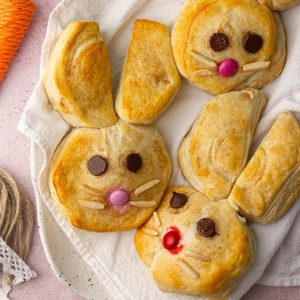 Close-up of baked Easter Bunny Biscuits on a plate with almond whiskers and candy faces.